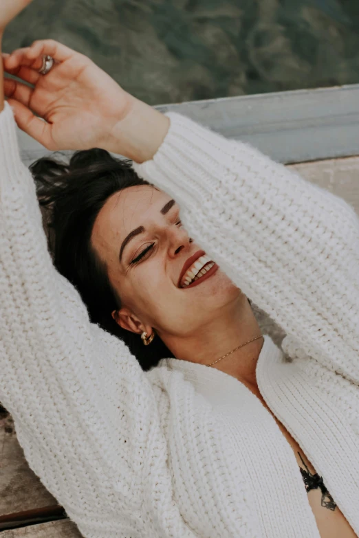 the young woman smiles and holds her hand out while sitting on a bench