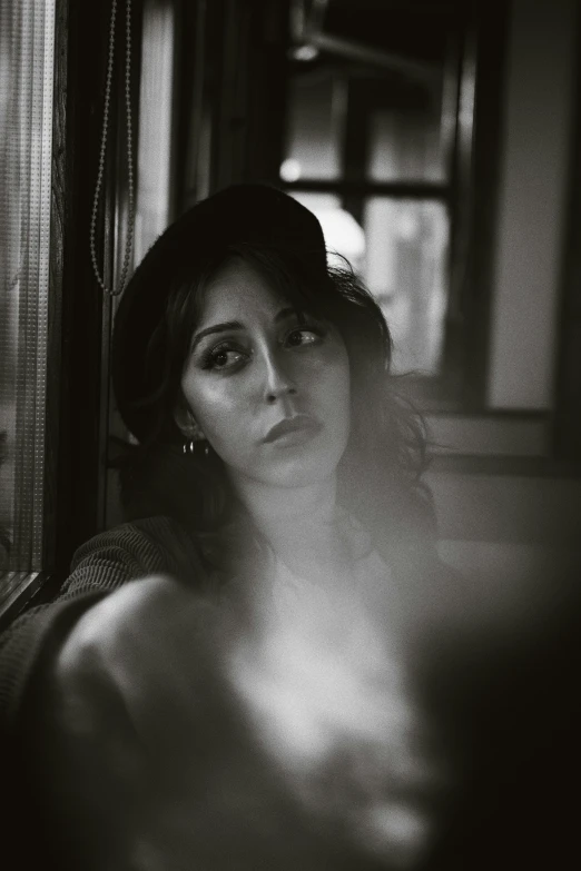 woman posing in black and white with her arm around a window