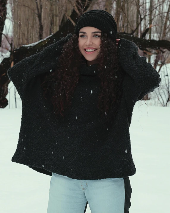 a young woman is wearing a black jacket while standing in the snow