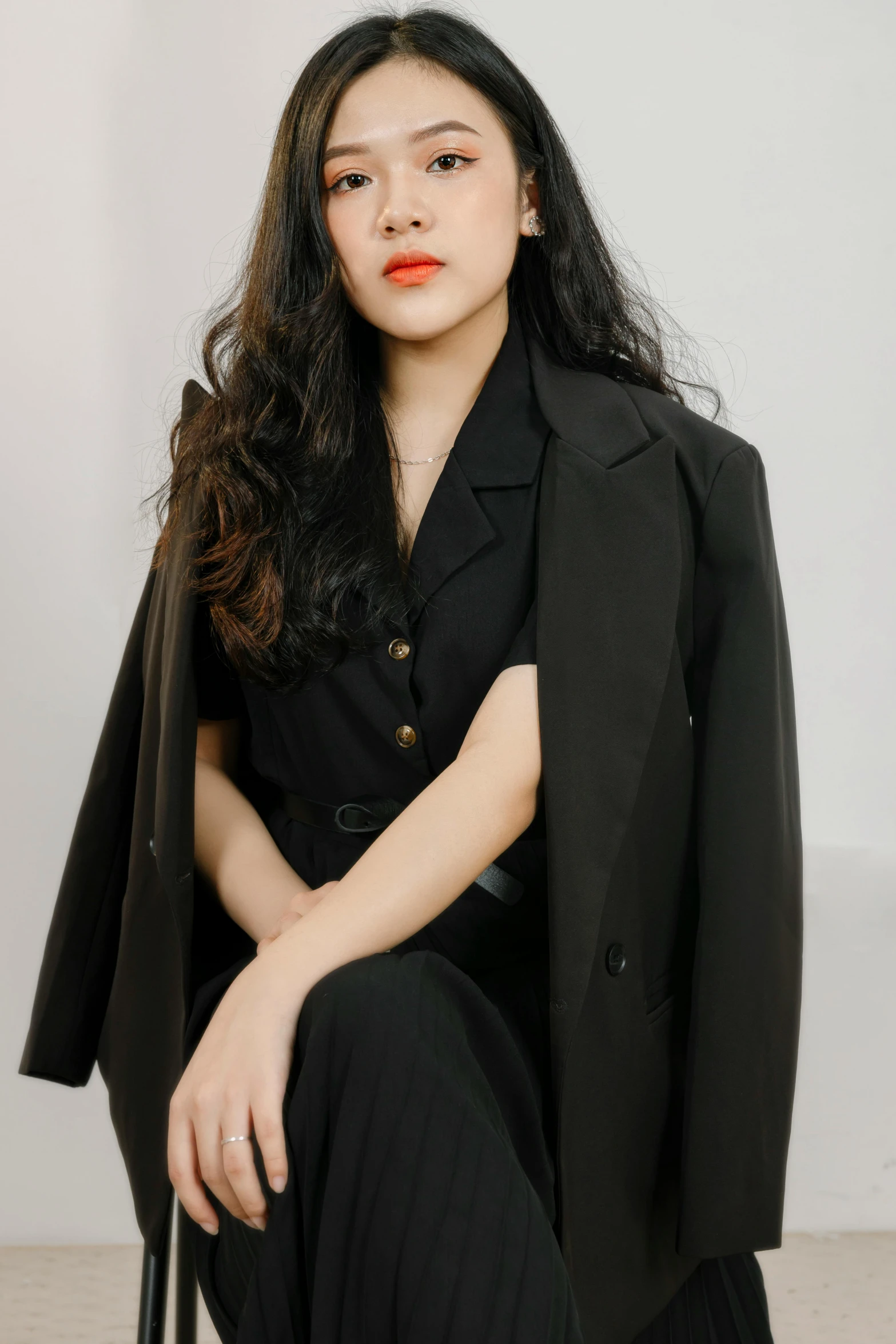 a woman sitting in a chair wearing black jacket and a black shirt