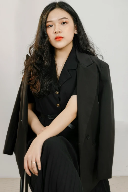 a woman sitting in a chair wearing black jacket and a black shirt