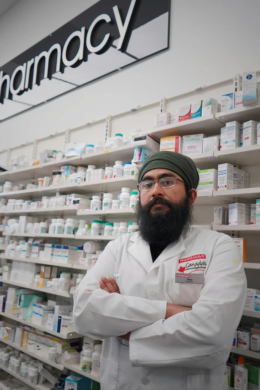 a pharmacy pharmacy employee stands in front of a rack with medicine on it