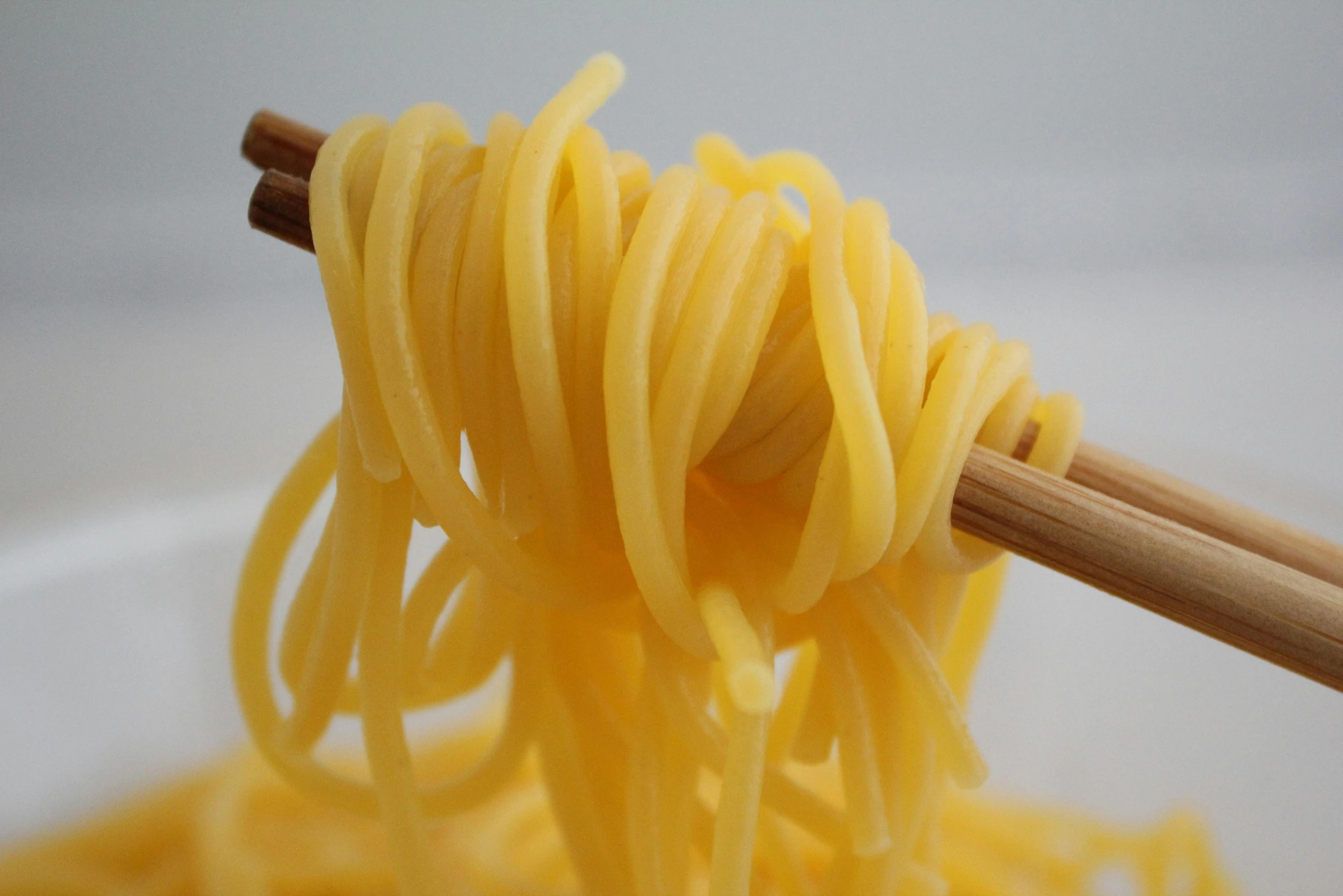 a bowl filled with noodles and two wooden chopsticks