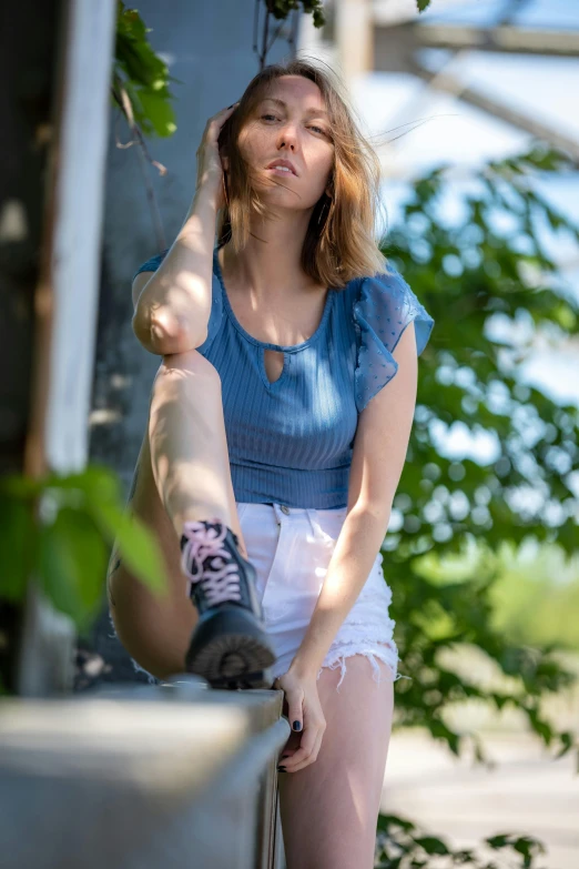 a woman in short white shorts standing next to plants