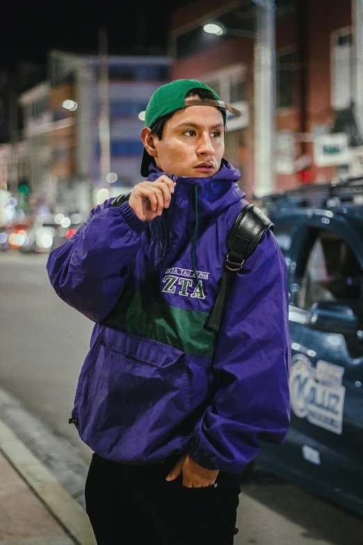 a man wearing a green and purple jacket posing for the camera