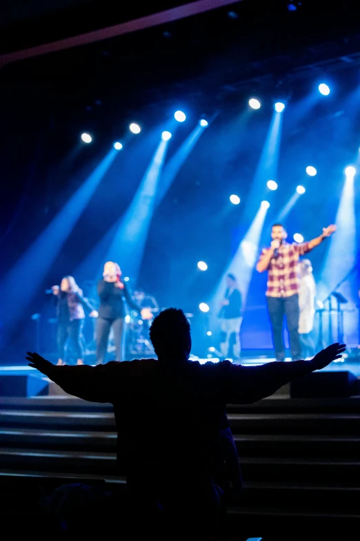 a band of men standing on stage under a lot of lights