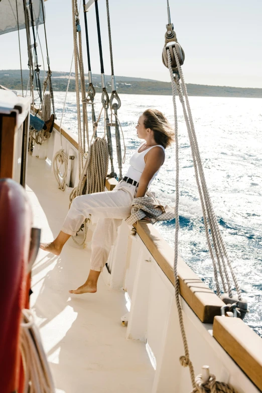 a woman looking over the railing of a sailboat at sea