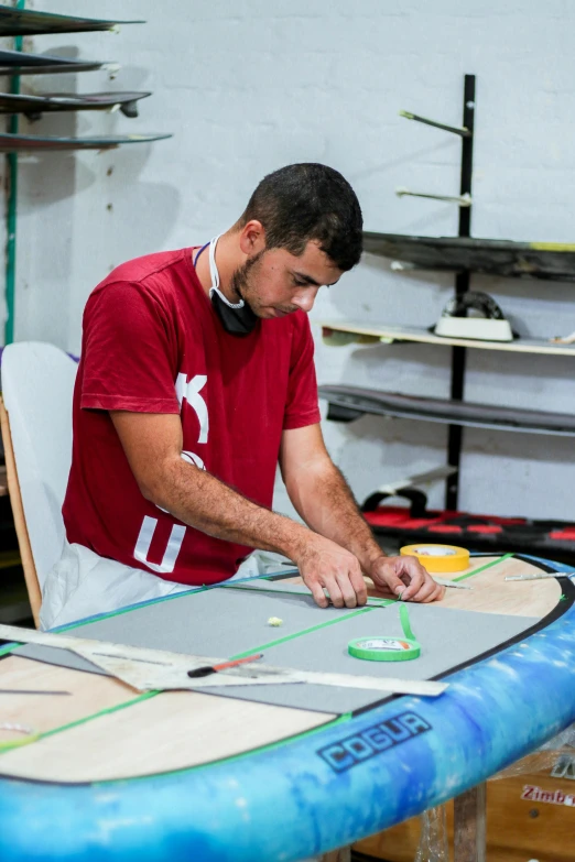 a man standing over a surfboard in a shop