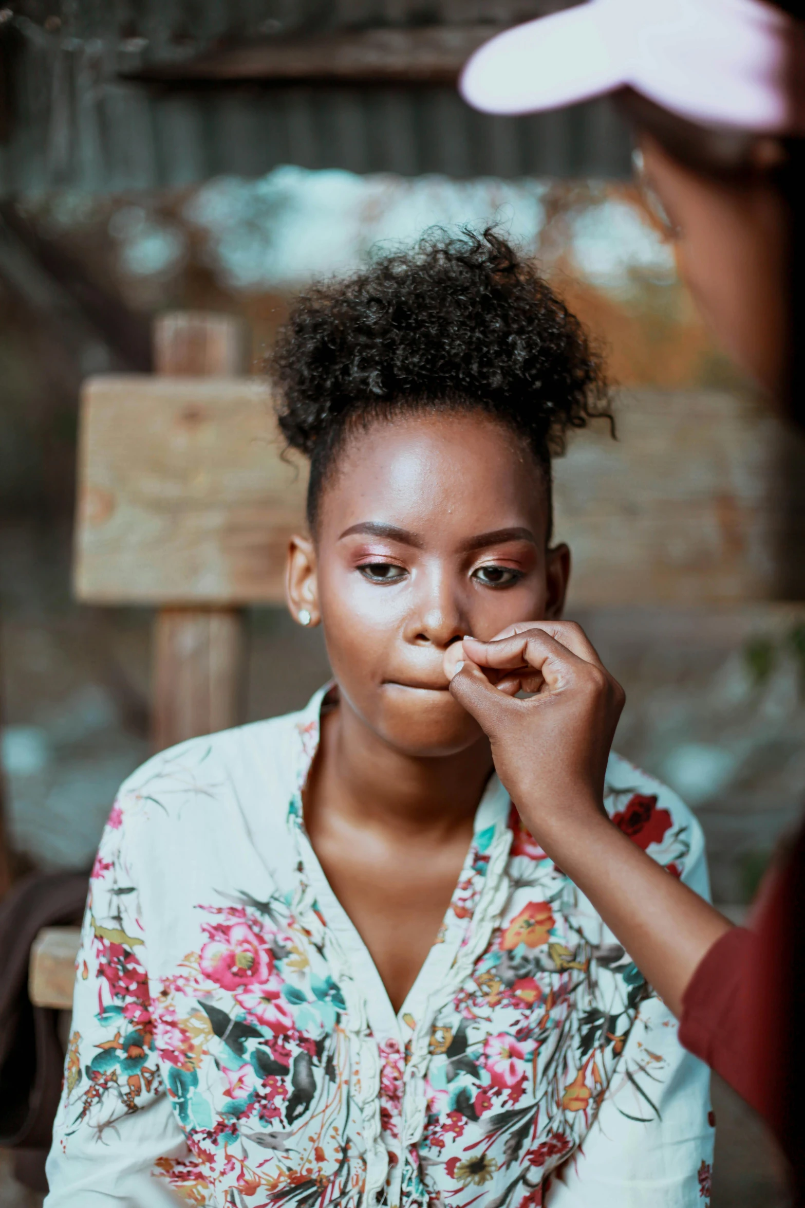 a woman standing next to a woman who is touching her nose