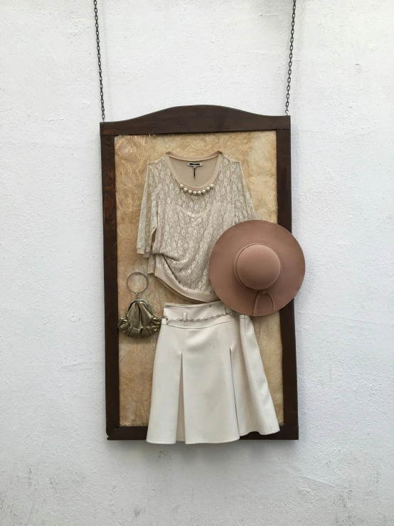 a wooden art piece that looks like a women's white dress and brown hat