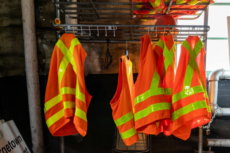 a group of safety vests hanging in front of a brick wall