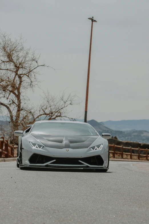 the front of a grey car parked on the side of a road