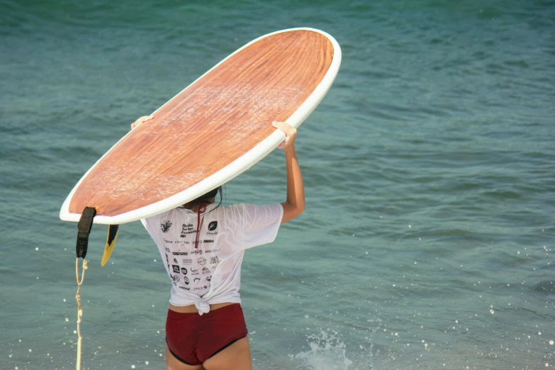 a surfer walking into the ocean carrying his surfboard