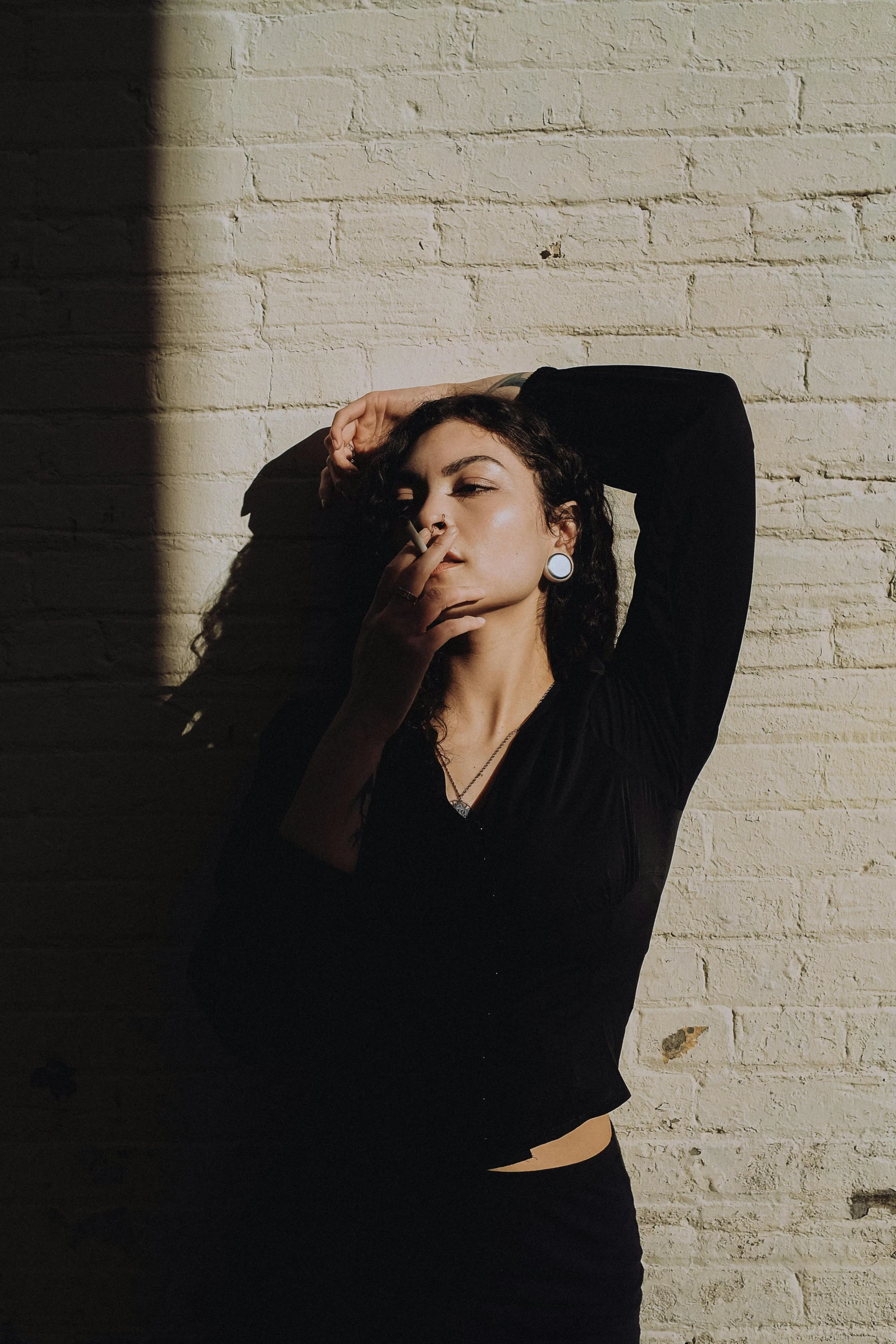 a woman posing for a portrait next to a brick wall