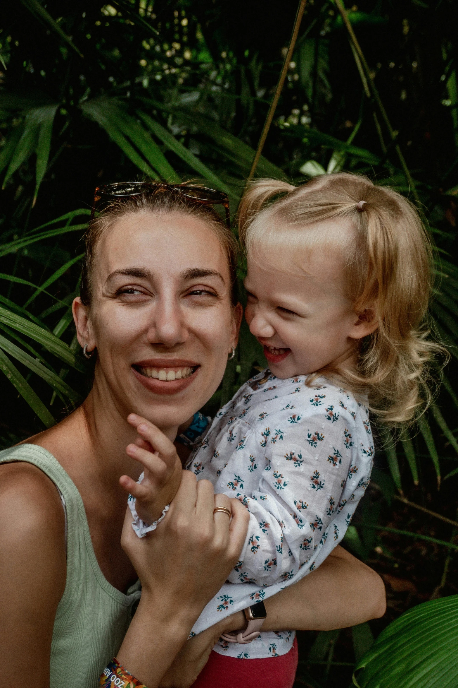 a woman holding a little girl near the trees