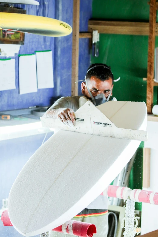 a man standing in a shop with a white surfboard