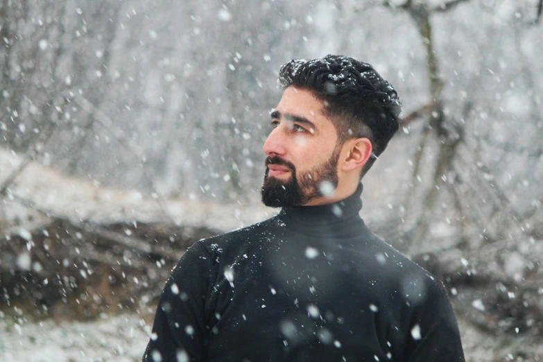 a bearded man stands in the snow outside