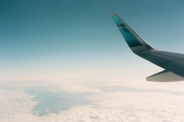 an airplane wing is seen above some white clouds