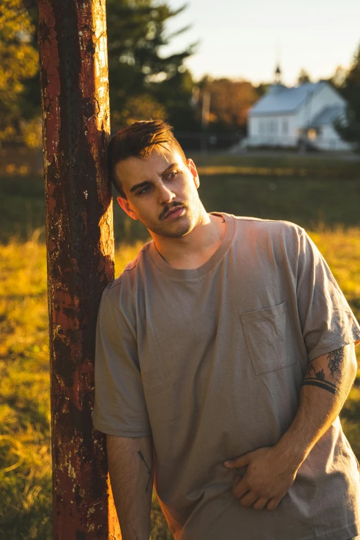 a man standing next to a tree in the grass