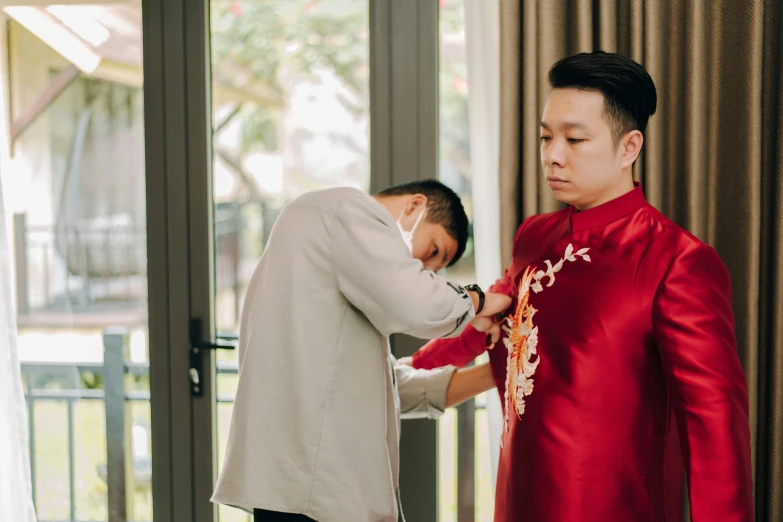 a man adjusting a woman's neck in a red dress