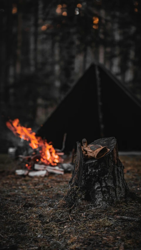 a campfire with the tent on fire in the background
