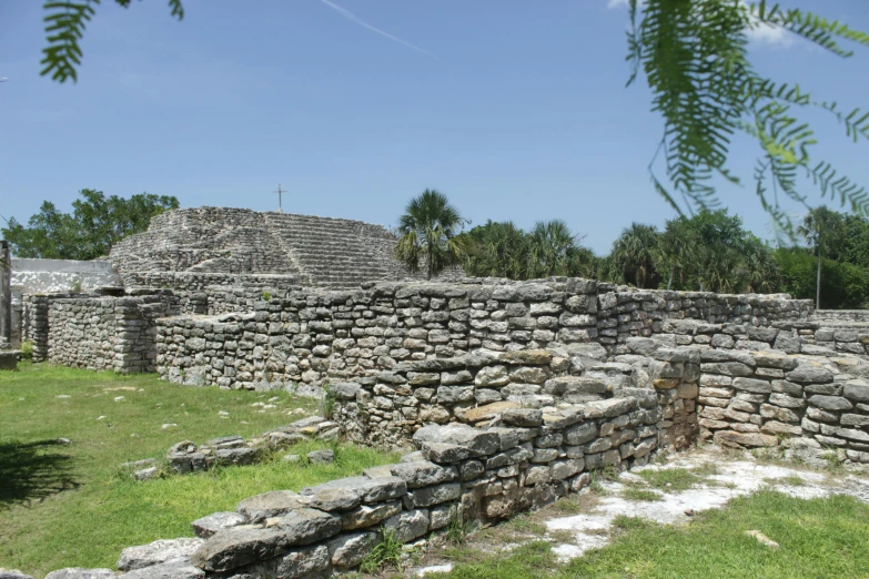 a stone wall next to trees and grass