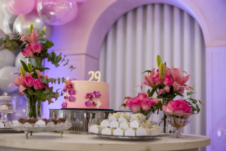 a table with cakes and flowers next to balloon decorations