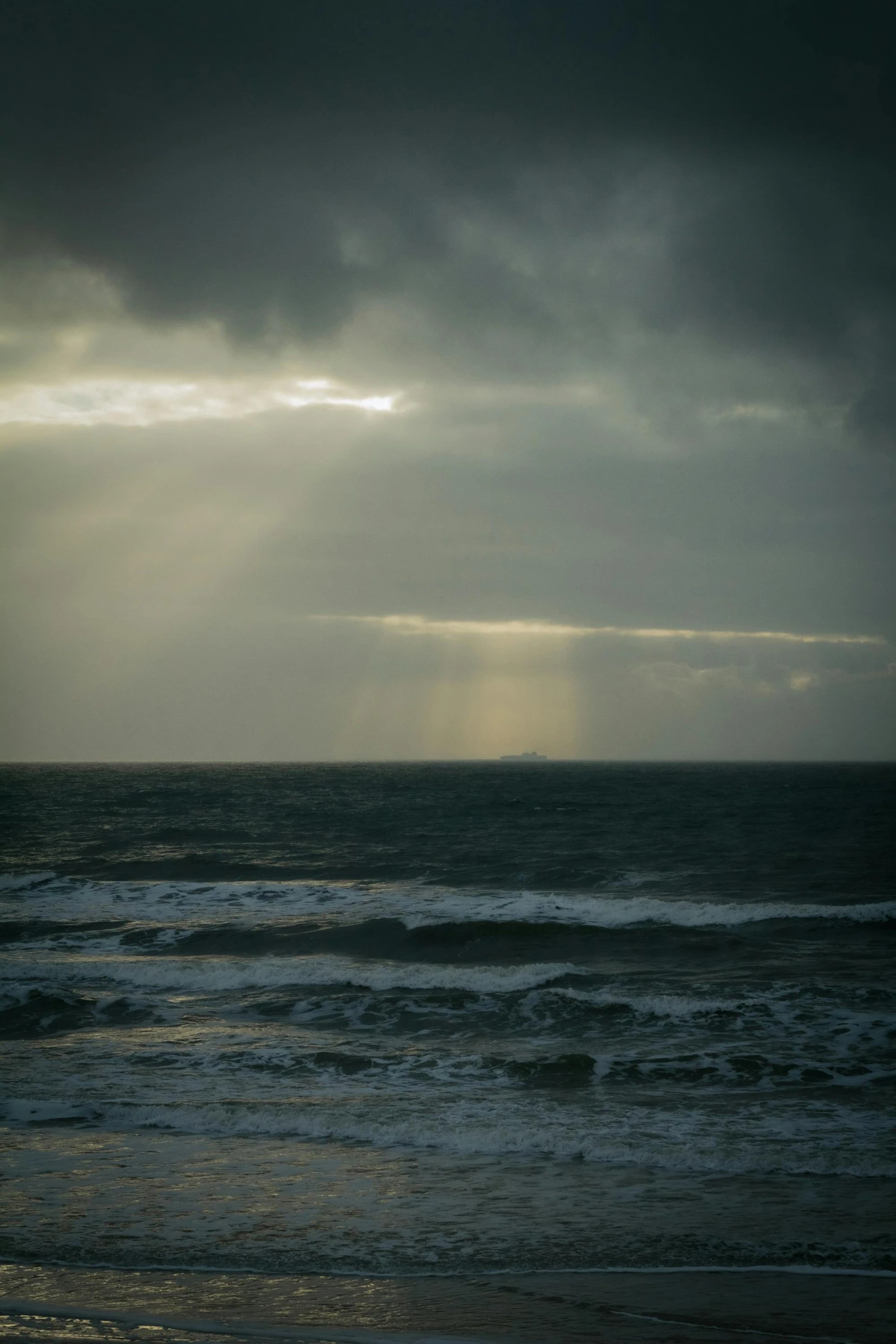 the sun is shining down on some dark gray clouds over the ocean