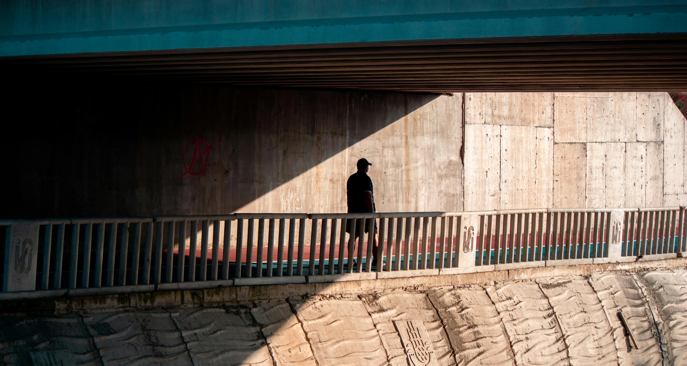 a man is walking down the sidewalk in the shadows