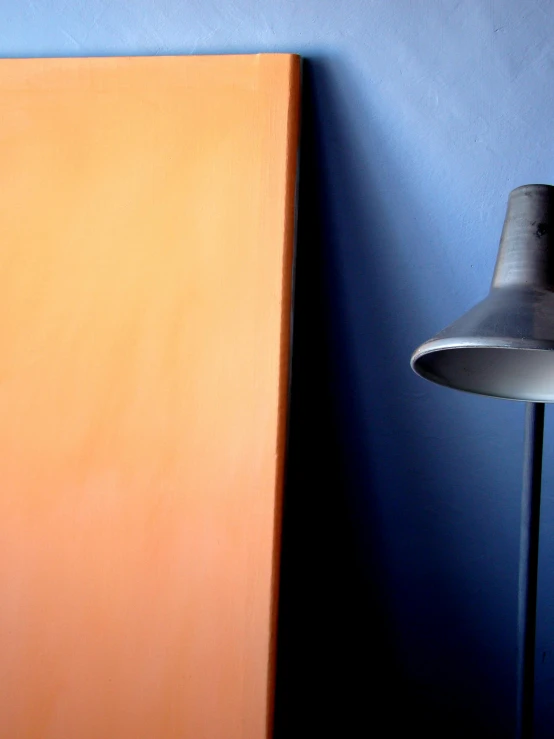 an orange sideboard and a gray lamp against a blue wall