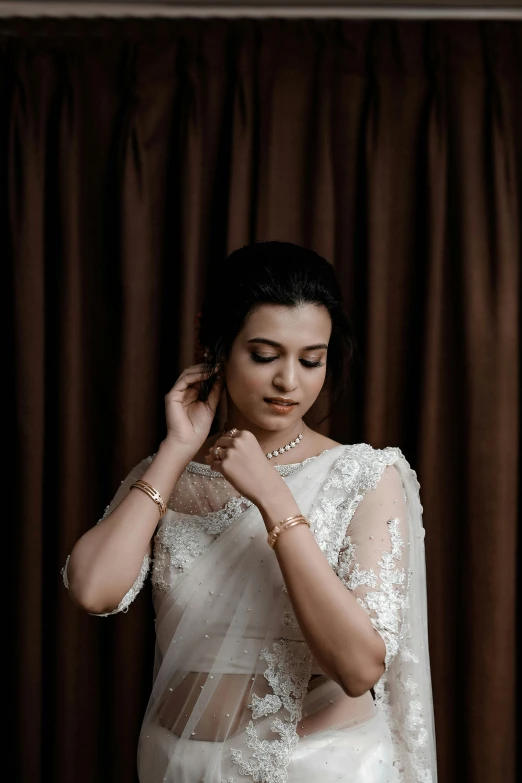 a bride stands before a curtain with her hands on her shoulder