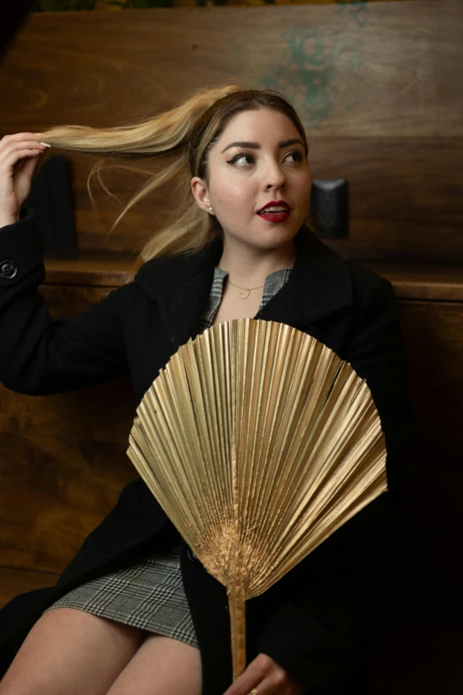 a woman in shorts and a jacket holds a golden fan