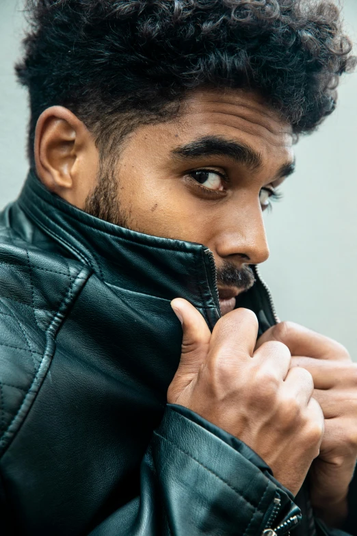 a young man wearing a leather jacket is looking over his shoulder with a moustache