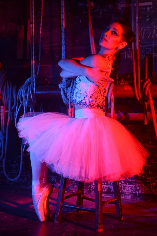 a woman sitting on top of a stool wearing a dress