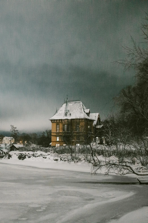 the snow covered road is next to a house