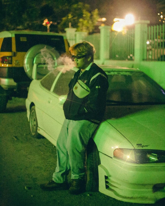 a man leaning on the back of a parked car