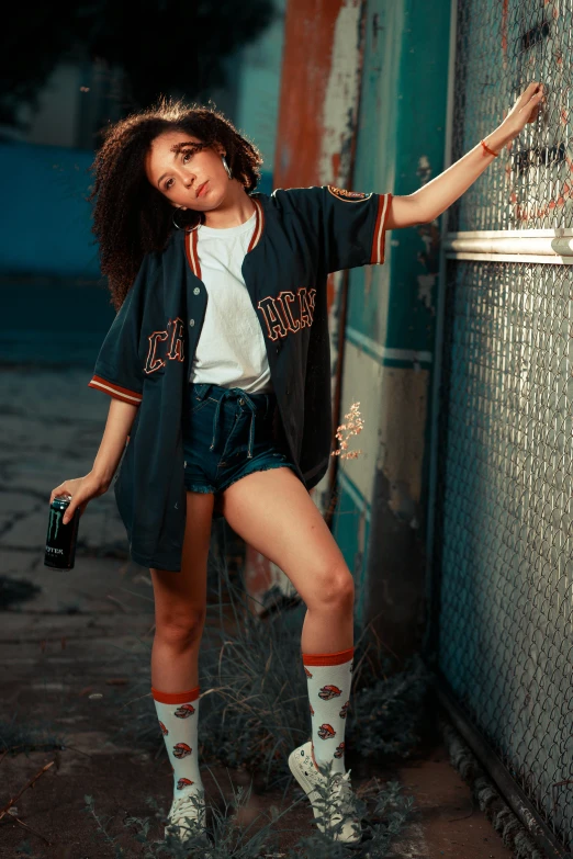 a woman leaning against the wall while wearing short shorts