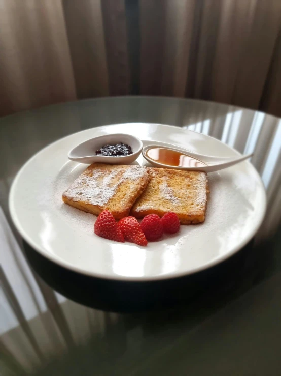 a plate has powdered waffles, raspberries and er on it