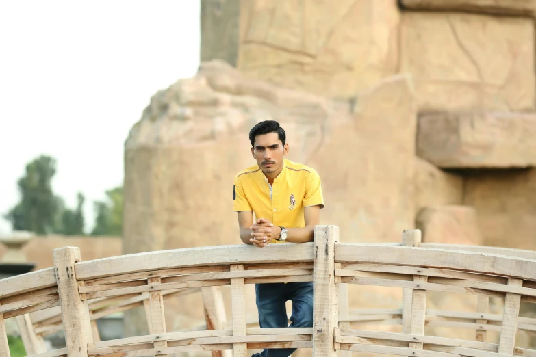 a man standing on top of a wooden bridge over a stone wall