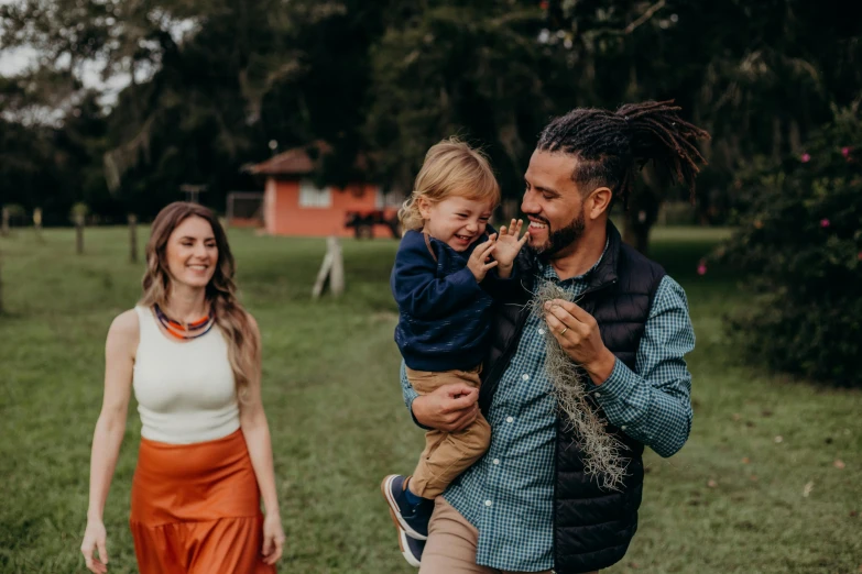 a man holding a toddler girl while she walks next to him