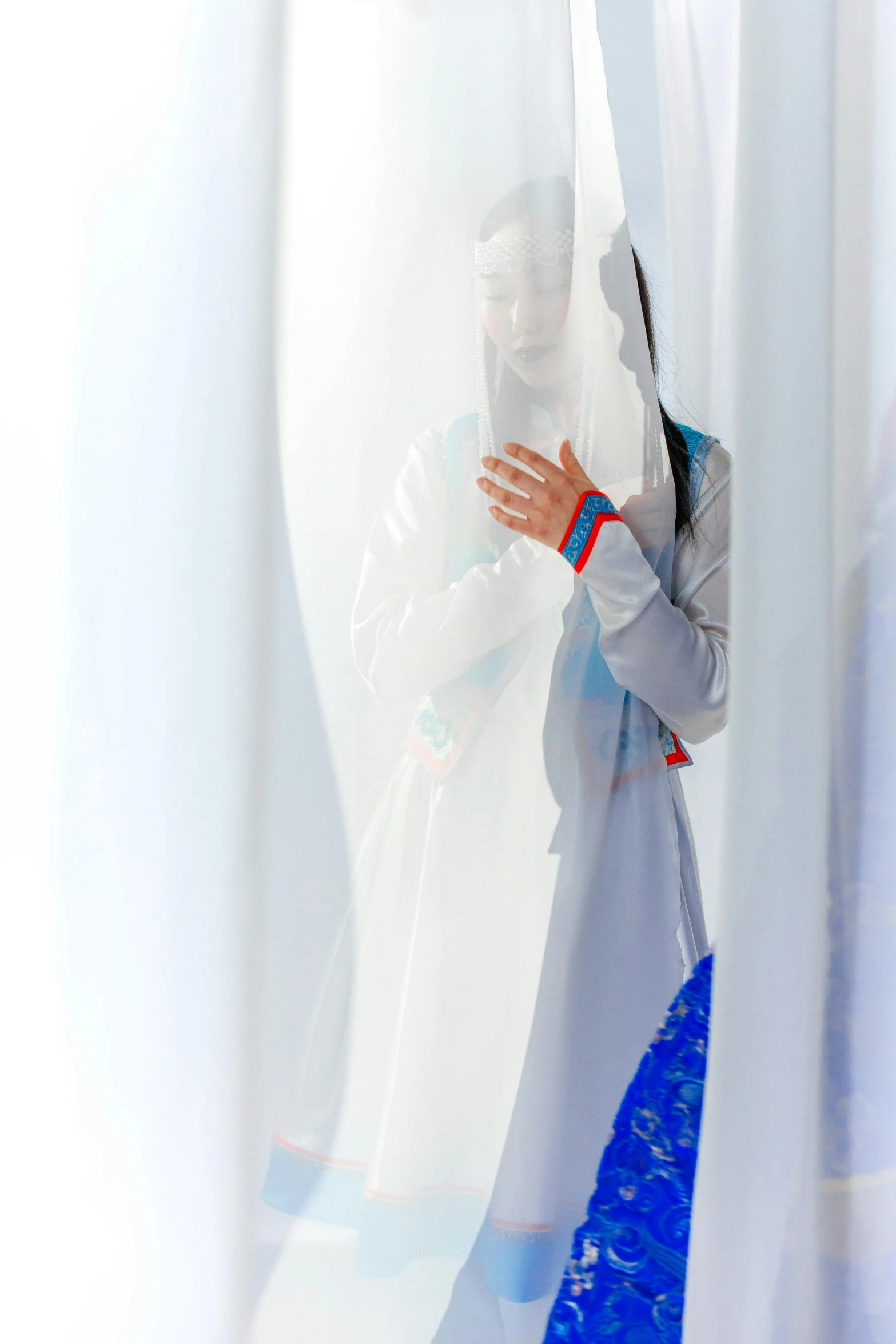 a woman looking through some curtains in a room