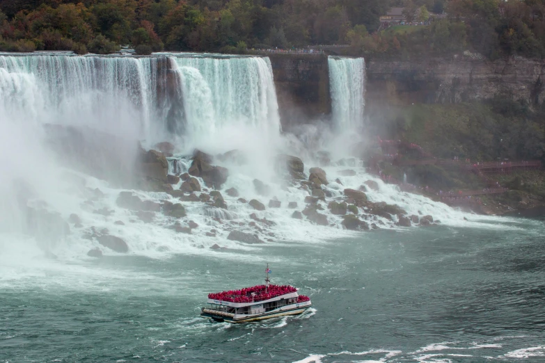 a boat on water surrounded by a large waterfall