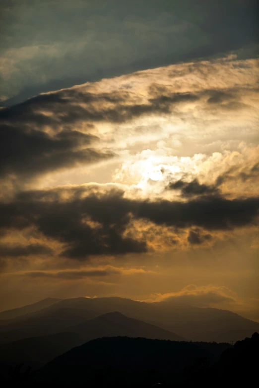 an airplane flies in the sky while sun is coming up behind a mountain range