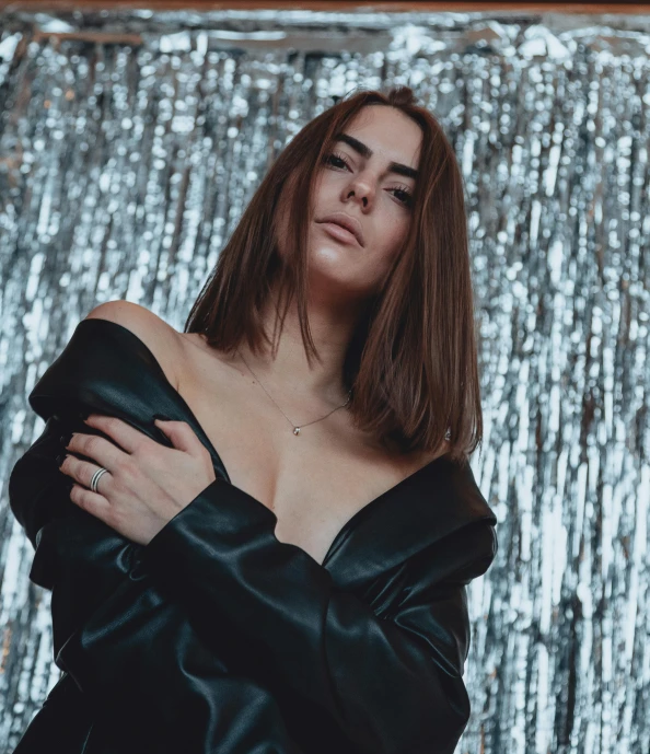 a women in a leather top posing in front of a foil wall