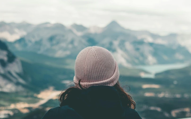 a woman looks over a vast valley in the mountains