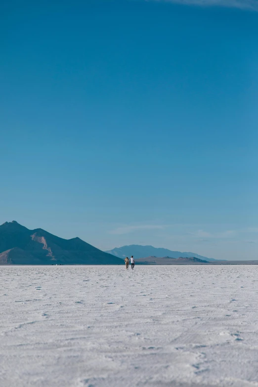 two people on snow are flying a kite