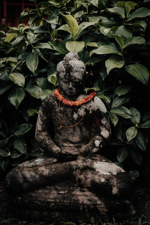 a stone buddha sitting in a grassy garden