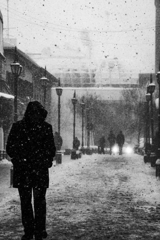 man in winter coat standing in snow near street lamp