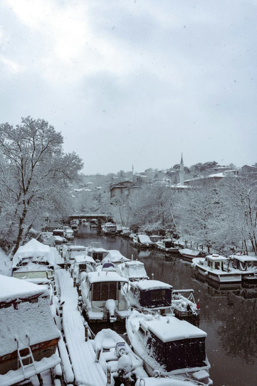 the snow is falling and there are cars parked on the street