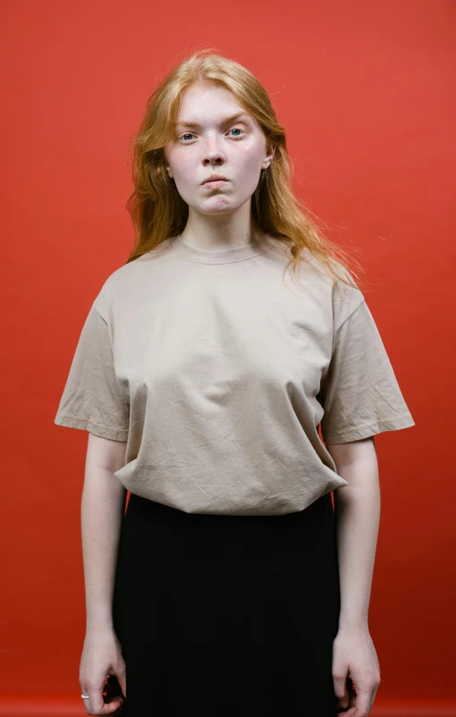 a girl with red hair standing in front of a red wall